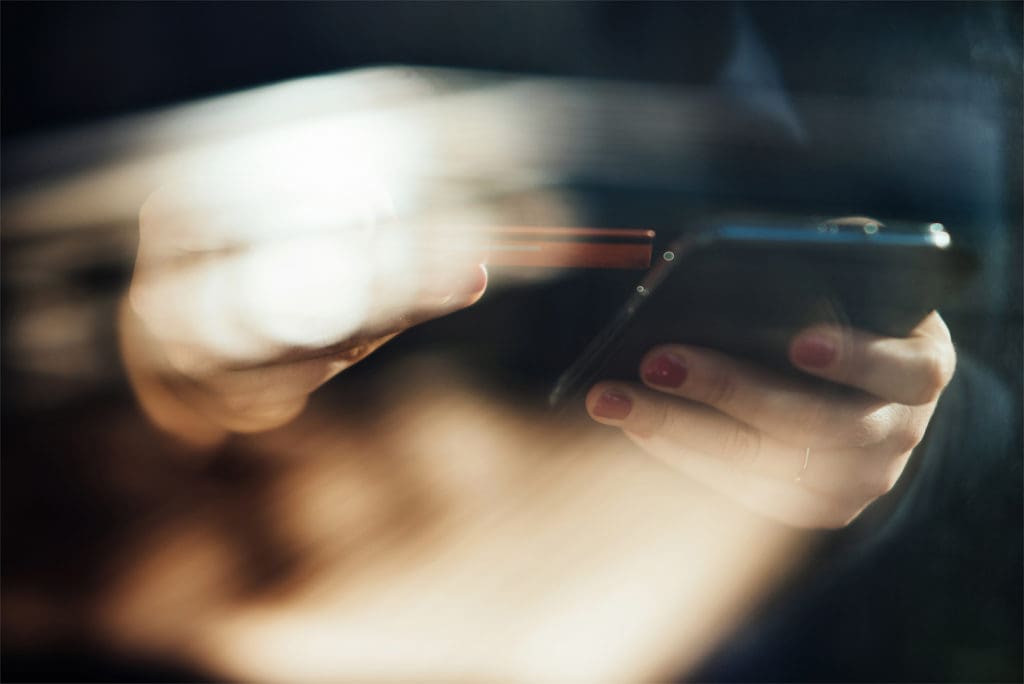 Shopping online with smartphone and credit card on hand.